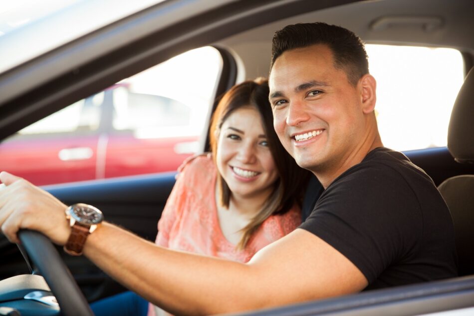 Young couple in care smiling out the window