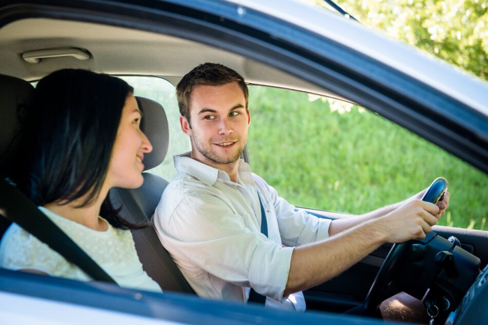 Two friends in car looking at each other and smiling