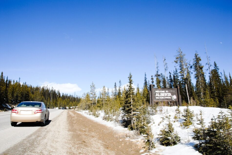 Car driving on highway next to "Welcome to Alberta" sign after importing car from the US