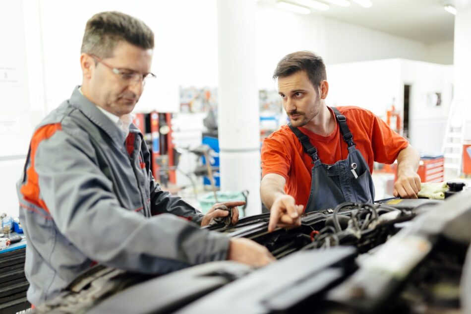 Two mechanics looking under hood of car