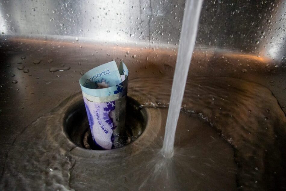 Canadian bills in sink drain with faucet running