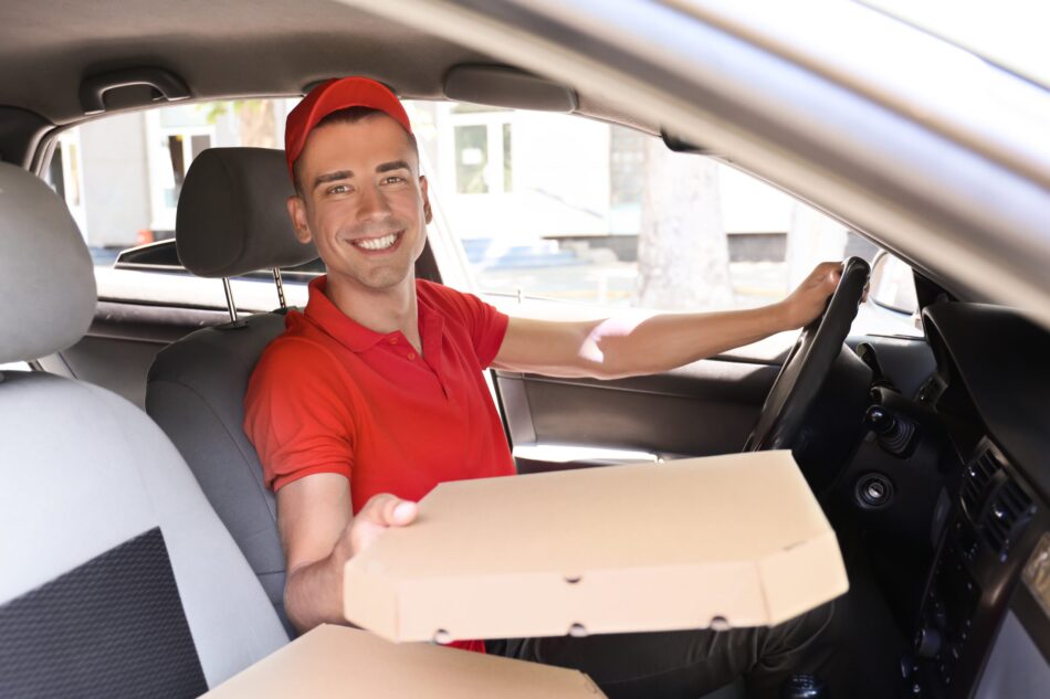 Driver in car handing a pizza out the window