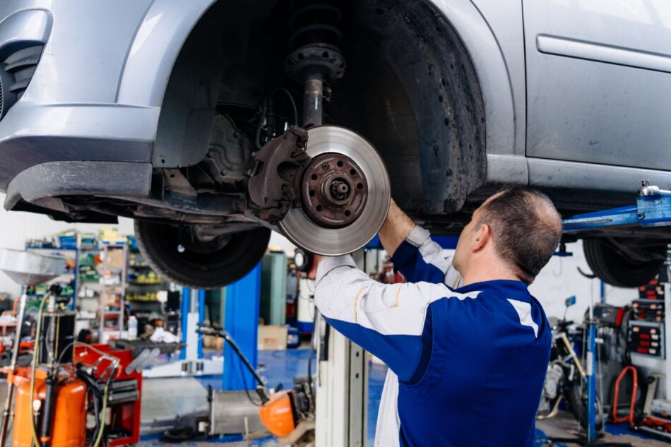 Mechanic with raised car working on tires