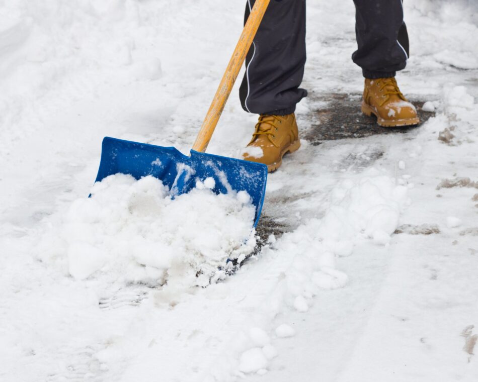 Feet and a snow shovel shovelling snow