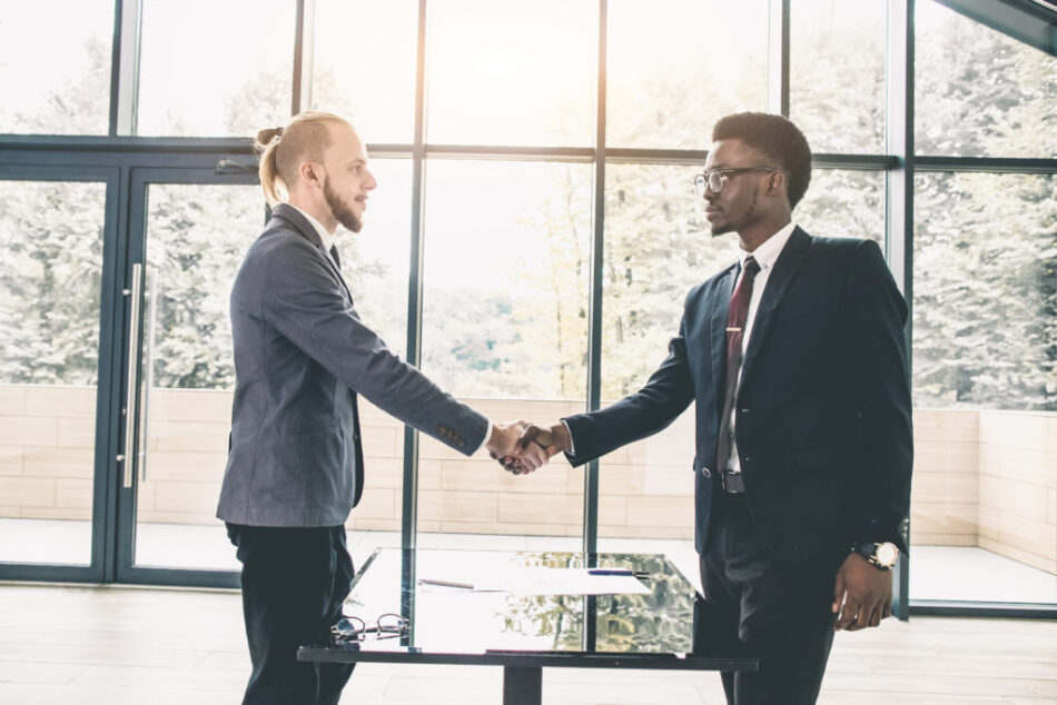 Young Caucasian businessman shaking hands to seal a deal with his partner pretty woman. Multiethnical group of business people having a business meeting