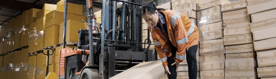 Woman in warehouse holding leg in pain