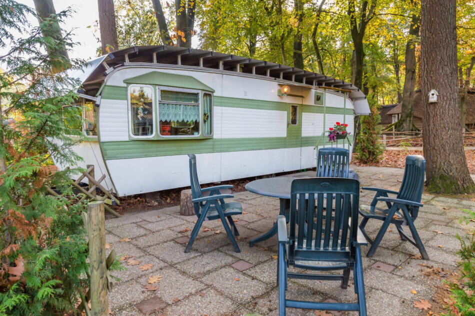 Retro white green caravan at a campsite in the middle of the forest.