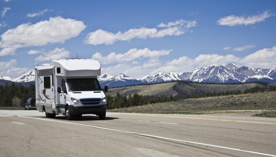 Motorhome driving on highway with snowy mountains in background
