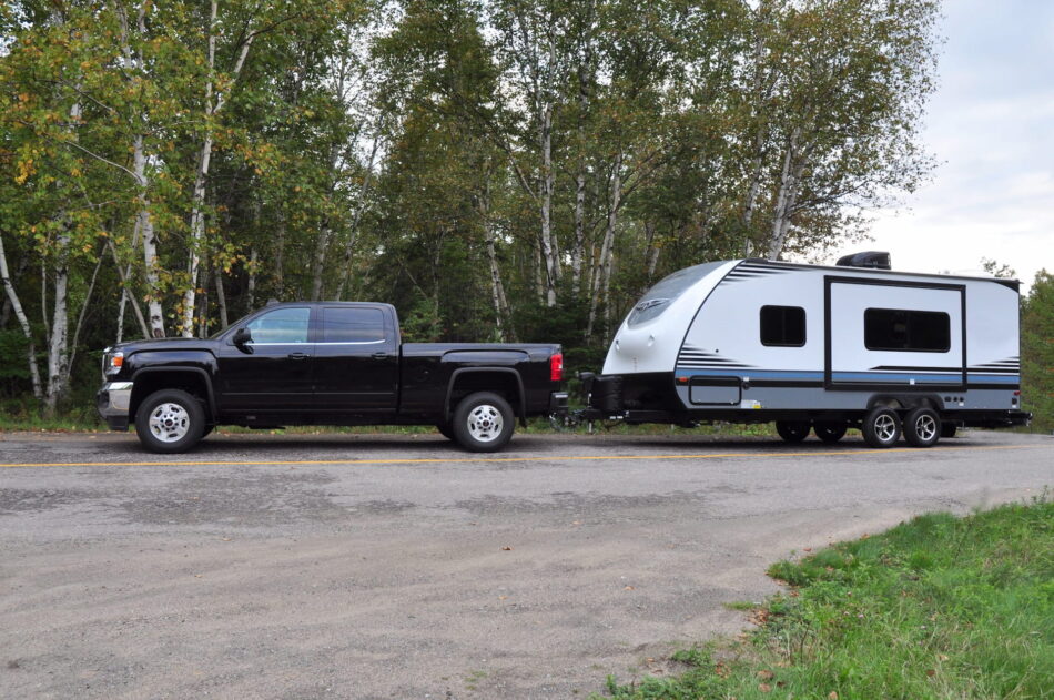 Parked large black truck with a large RV hitched behind it.