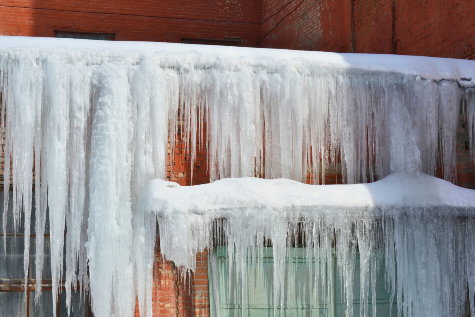 Long, big and dangerous icicles on a brick house roof