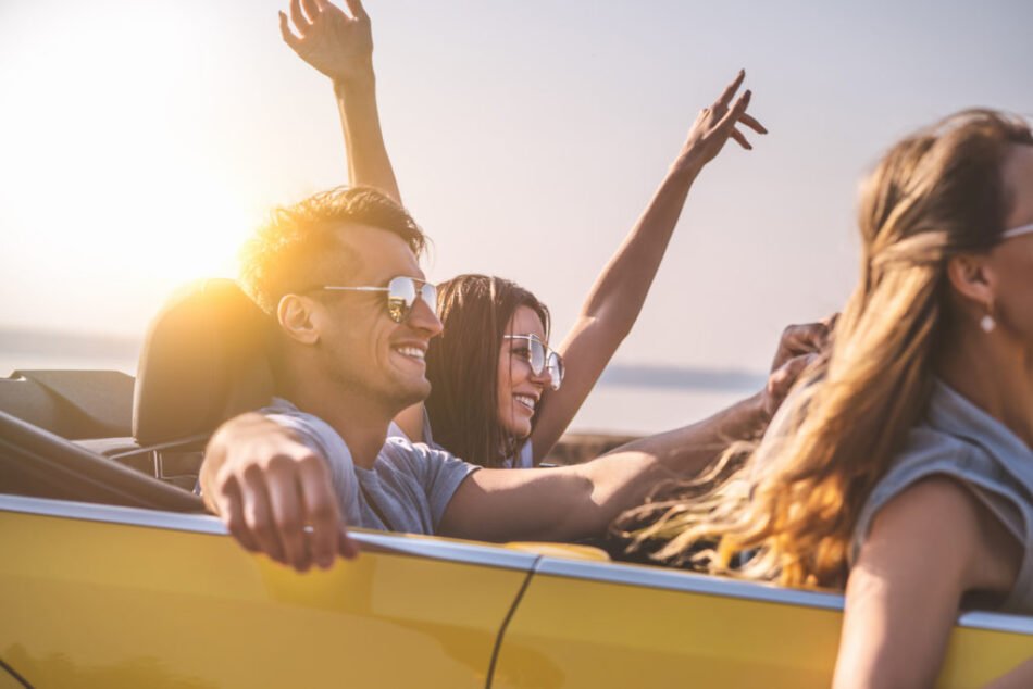 Friends travel in a yellow convertible on a sunny day