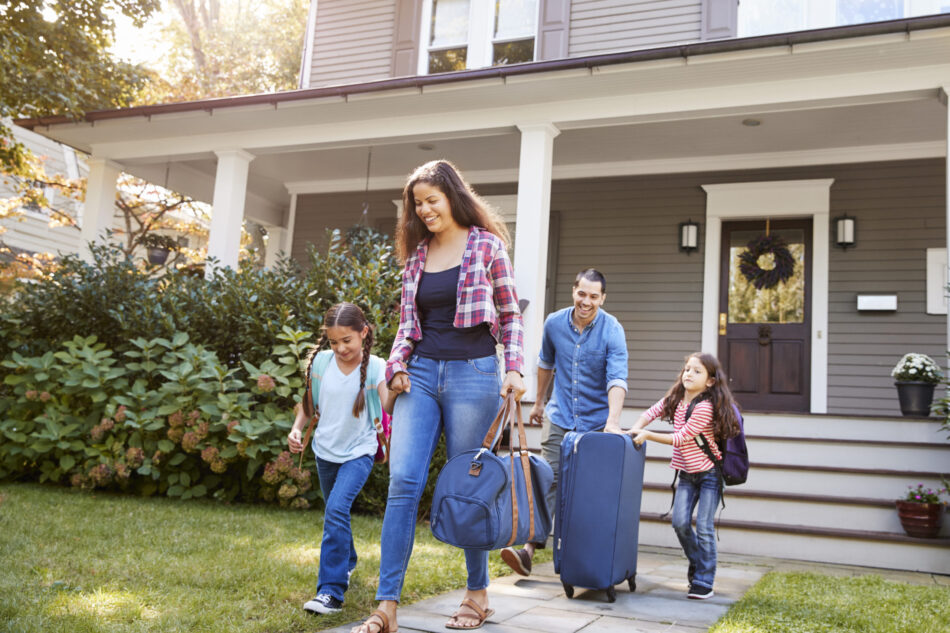 Family leaving their home with suitcases, excited for their vacation.