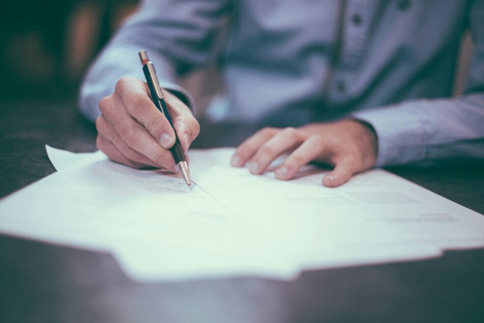Closeup of hand of a business professional signing co-insurance papers