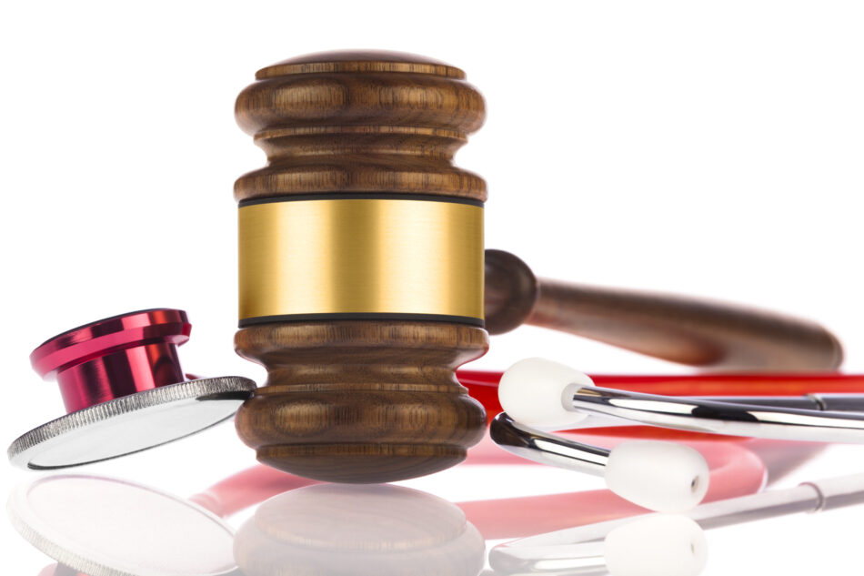 Medical Malpractice; stethoscope and gavel on white reflective surface.