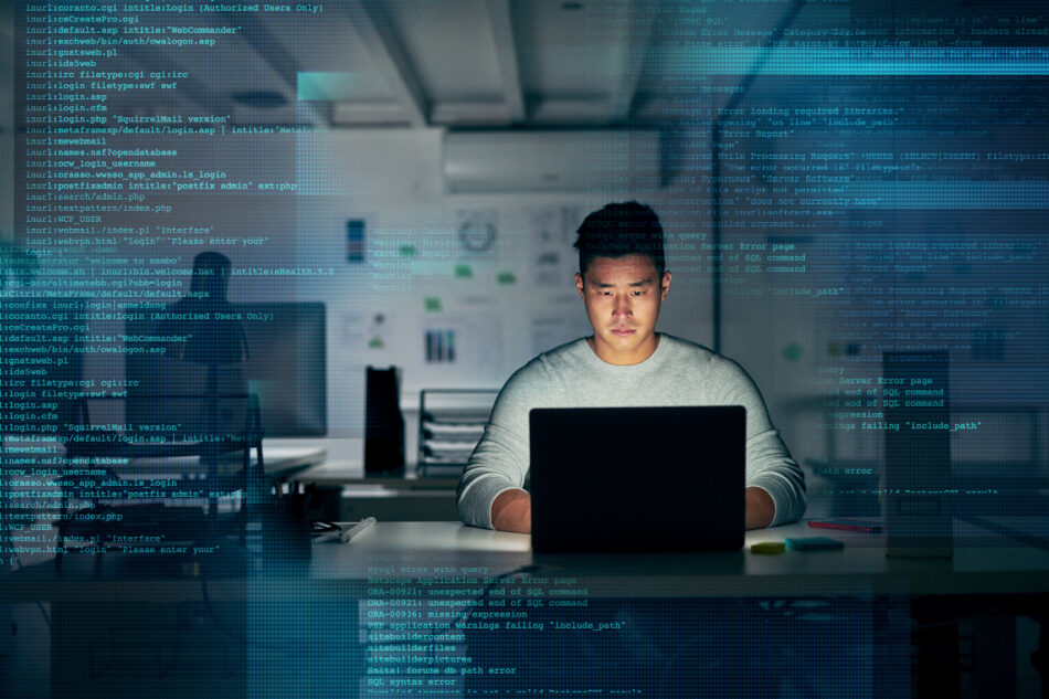 Shot of a young programmer using a laptop during a late night at work