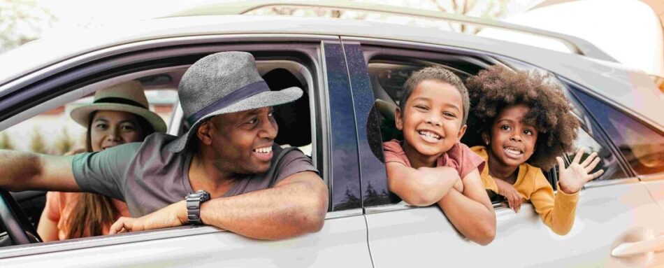 Young family smiling out the windows of their car