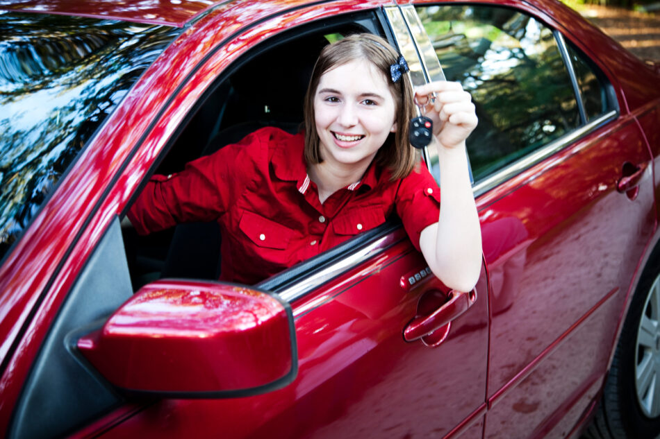 Teenage girl with her driver's license driving a new car and holding keys.