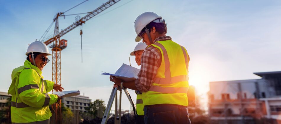 Two construction professionals on a jobsite with crane in the background