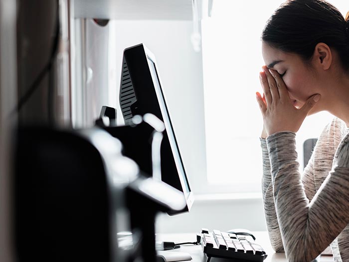 Woman in front of laptop looking stressed
