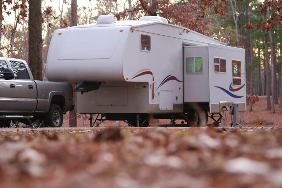 A newer fifth wheel parked in a campsite during autumn.