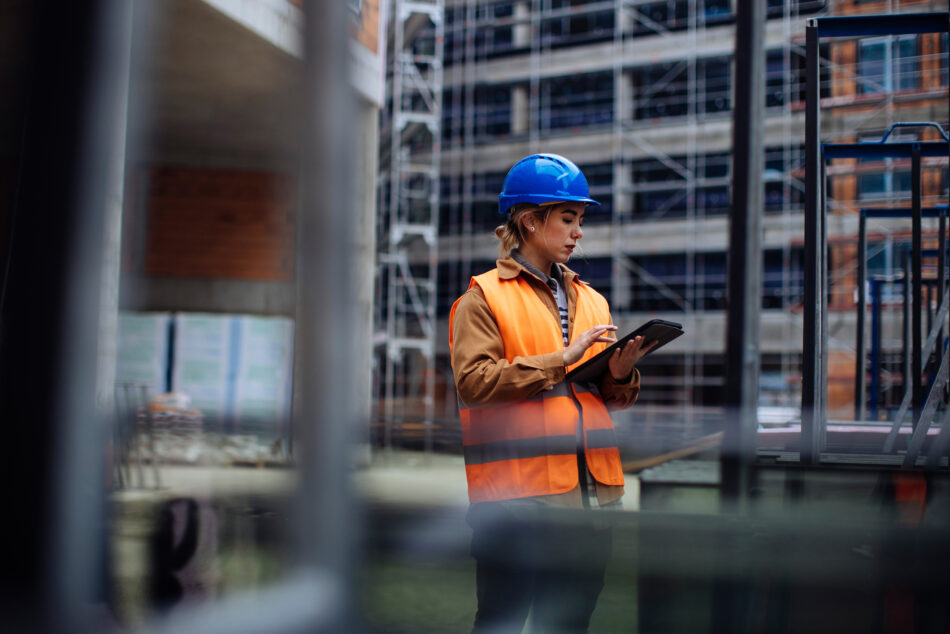 Young woman using her digital tablet at a construction site