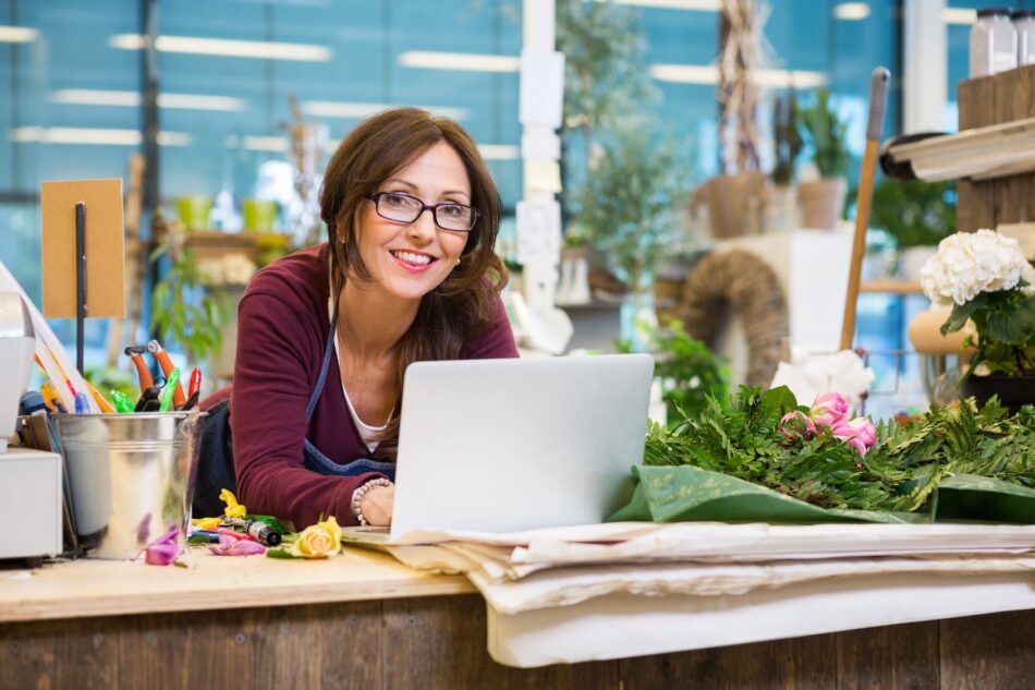 Woman behind floral shop counter smiling