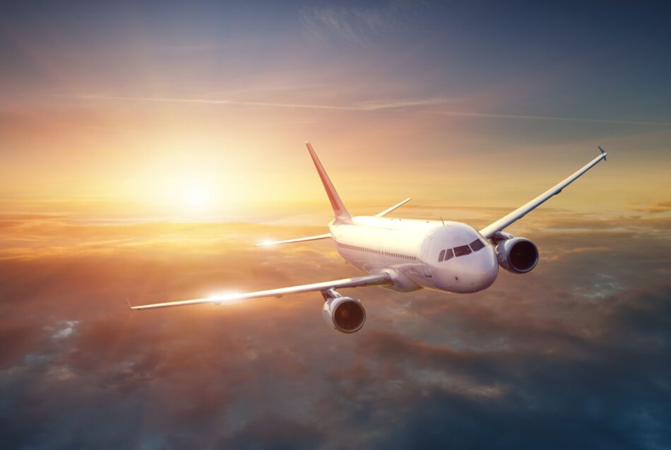 Airplane travelling through sunset sky