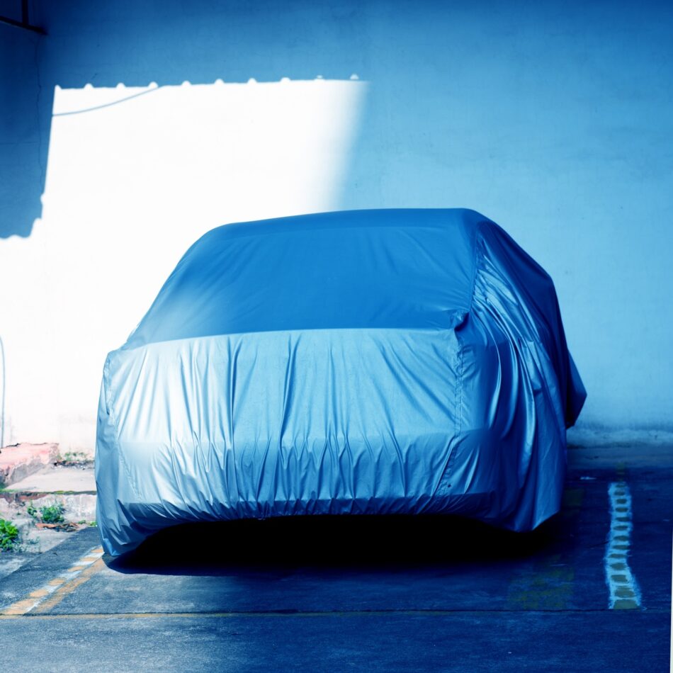 a car with cancelled insurance sitting covered in a garage