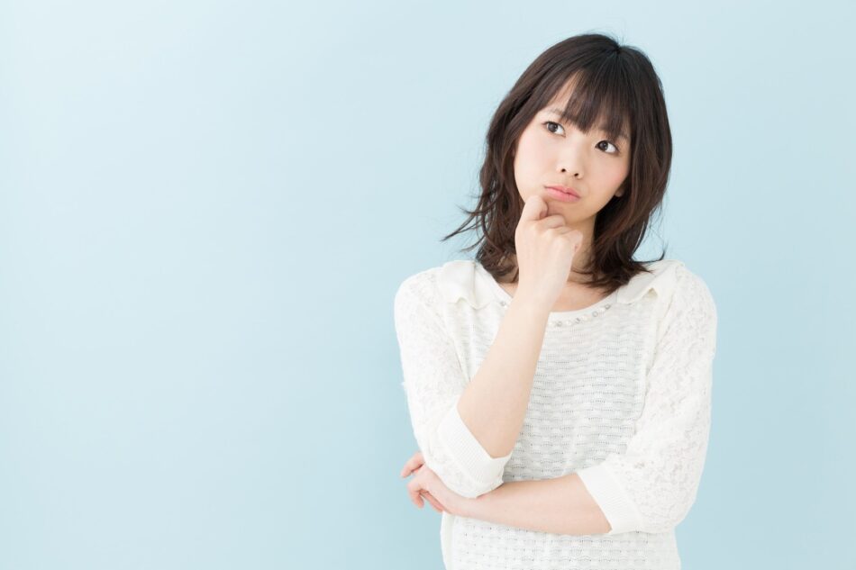 Woman in front of neutral background looking perplexed