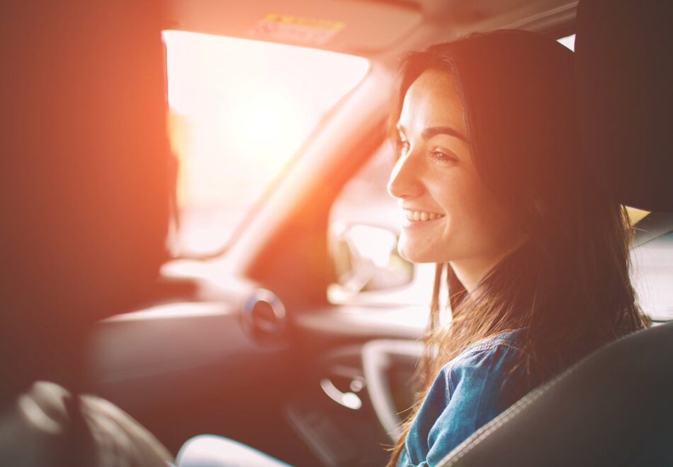 Young woman in passenger seat of a car smiling at the driver