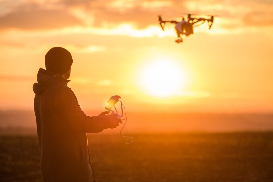Person flying a drone at sunset