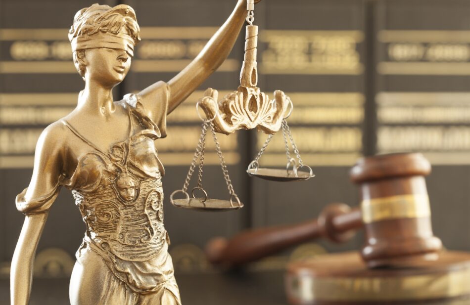 Statue of lady justice with gavel in the background