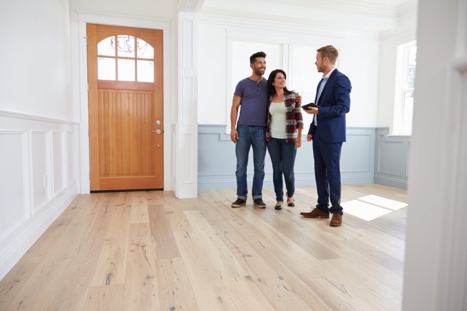 Young couple inside a clean bare house talking with a realtor