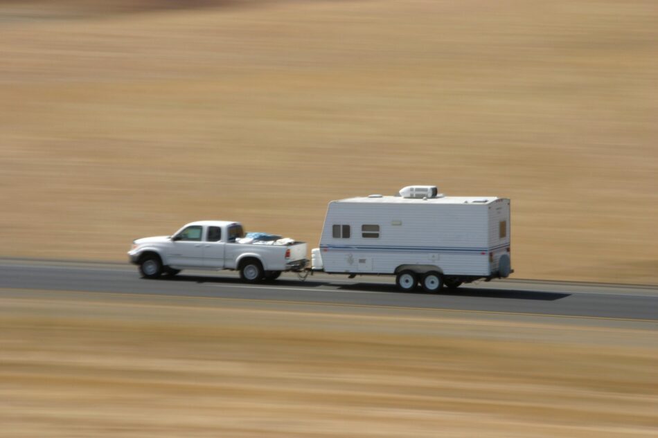 Truck towing RV Trailer while driving quickly down the highway