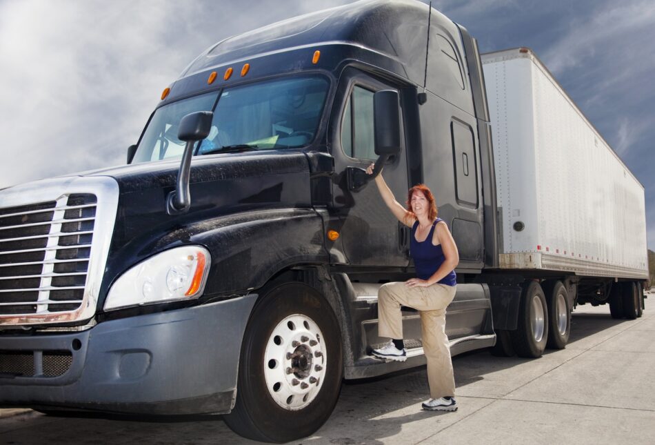 Trucker standing on commercial vehicle step and smiling