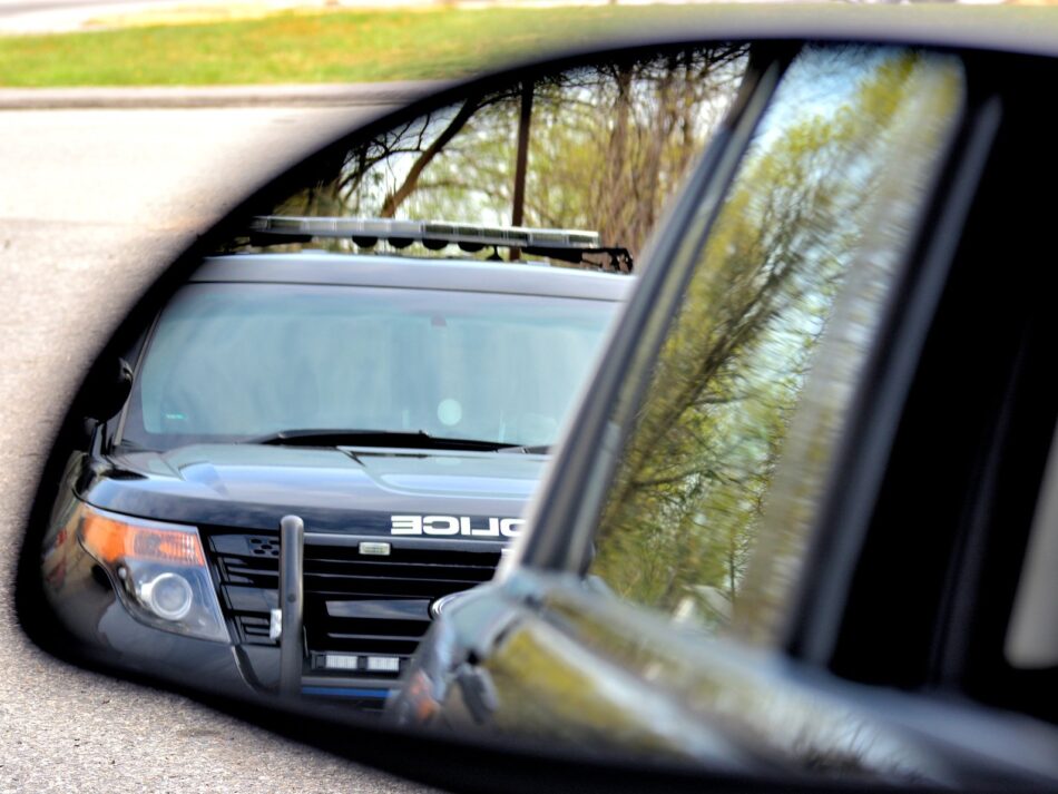 a police car viewed from a rearview mirror during a traffic ticket stop