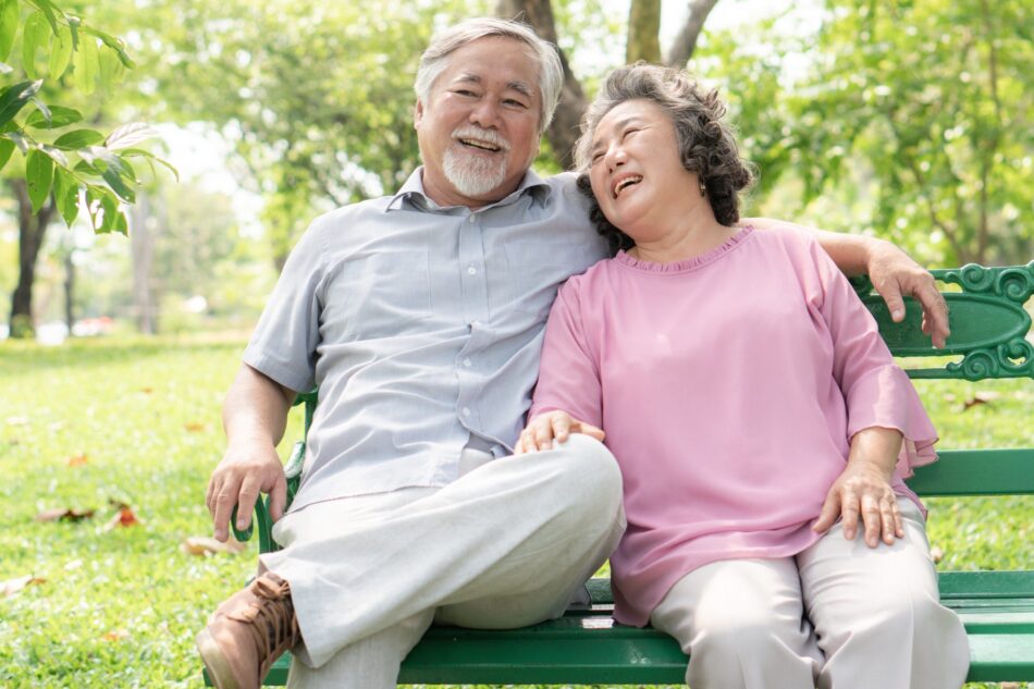 Senior couple on park bench laughing