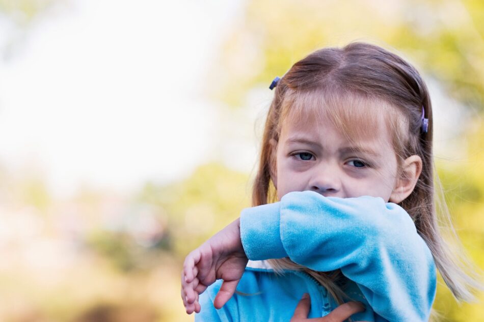 Young girl coughing into arm
