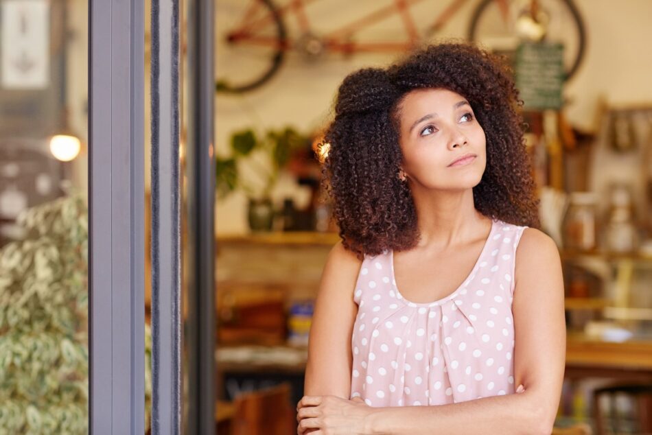 Woman in front of small business pondering insurance