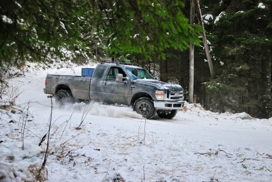 Large company truck driving through snowy forest
