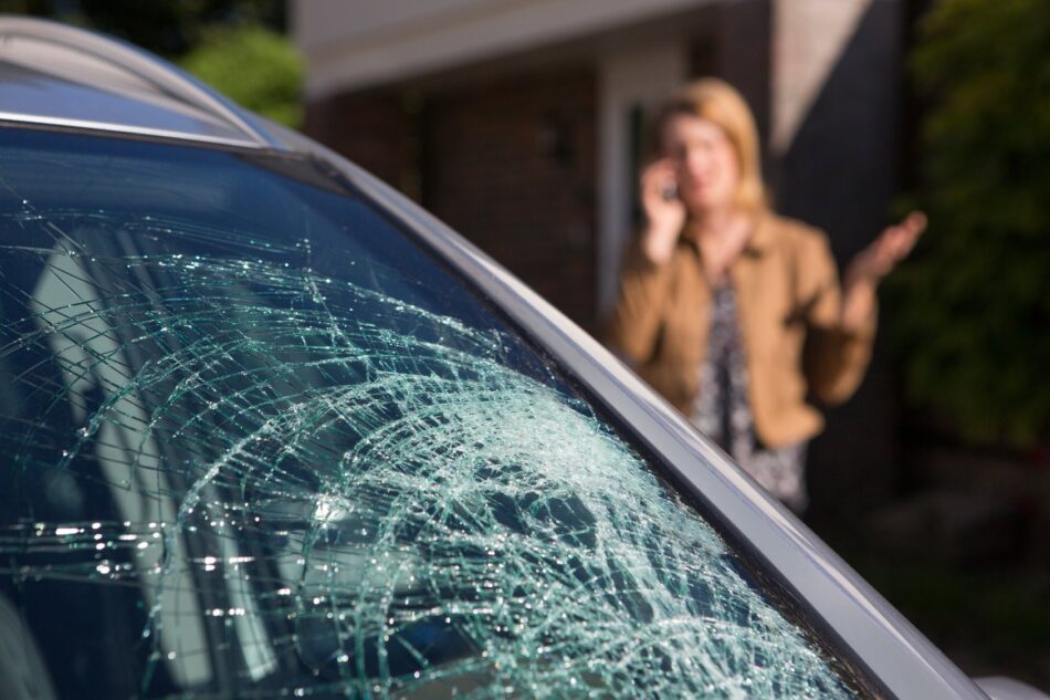 Smashed windshield with woman on phone in background