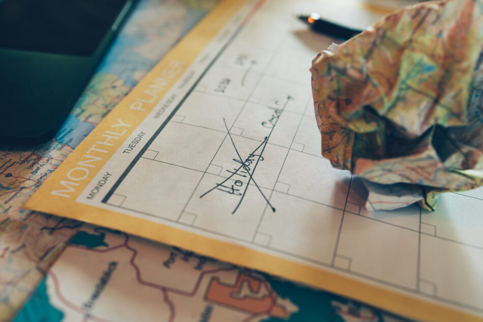 Tourist planning vacation with calendar and map. Cross line in holiday text and crump paper map . Cancel Travel, holiday, vocation and new year concept.
