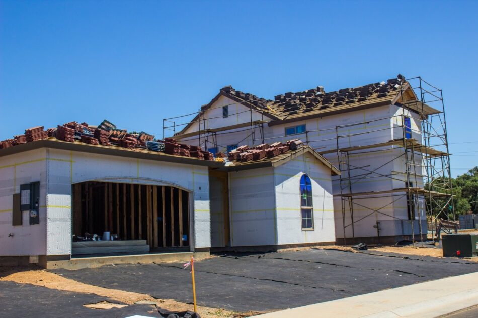 Exterior of home with scaffolding up to the roof for exterior and roof construction