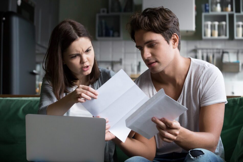 Young couple looking perplexed at paper policies