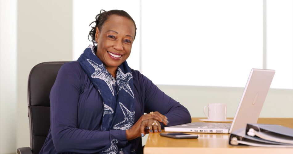 Underwriter sitting at desk with laptop open and smiling
