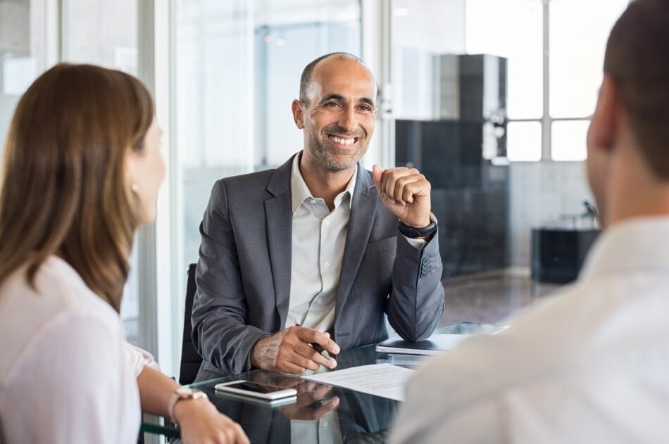 Young couple speaking with a broker in office setting