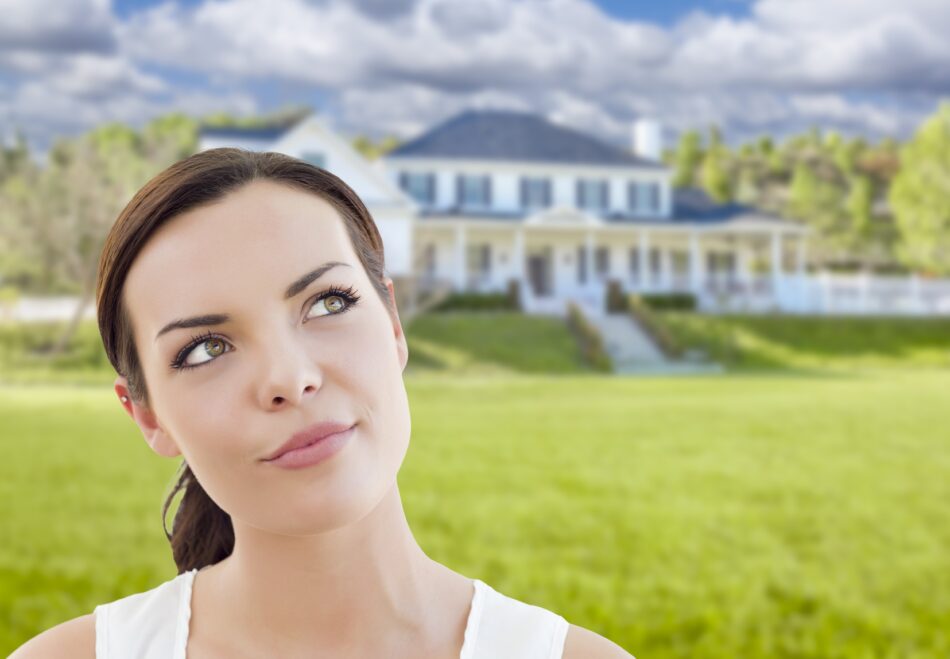 Woman looking perplexed with a large home in the background