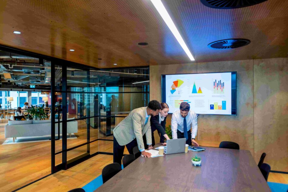 Group of business professionals in boardroom looking at laptop