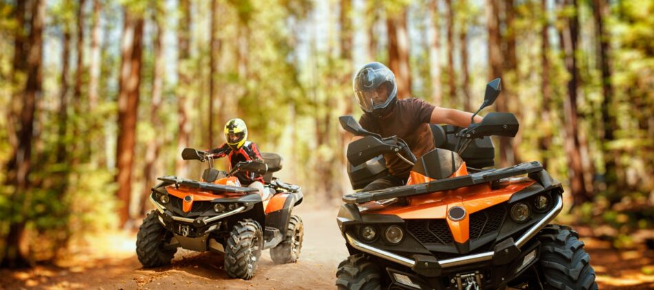 Two people riding off road vehicles through the forest