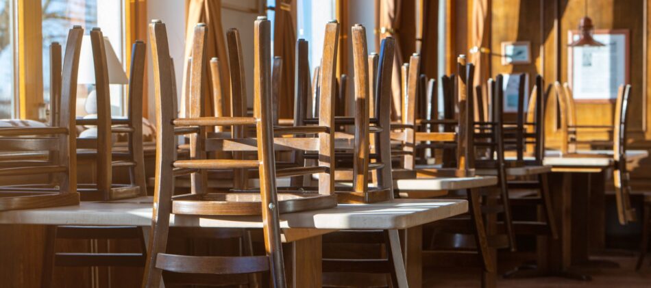 Tables in a restaurant with all chairs stacked on top of tables